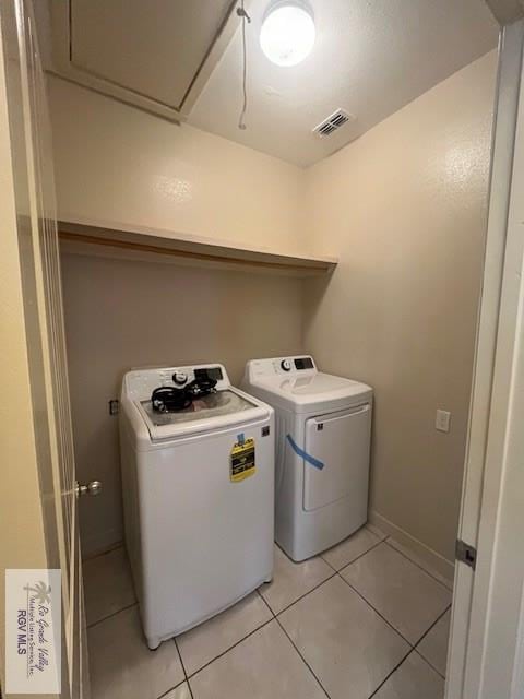 laundry room with washer and dryer and light tile patterned floors