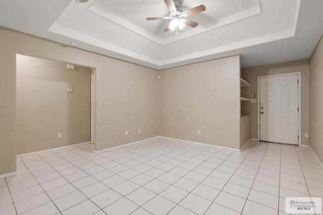 empty room featuring light tile patterned floors, a raised ceiling, and ceiling fan