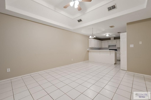 interior space featuring ceiling fan with notable chandelier, a raised ceiling, and light tile patterned floors