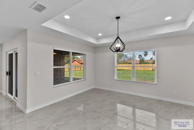 unfurnished dining area with an inviting chandelier and a tray ceiling