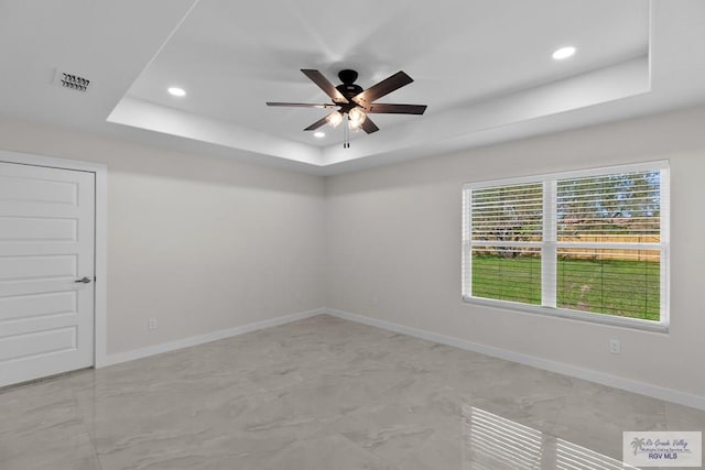 unfurnished room featuring ceiling fan and a raised ceiling