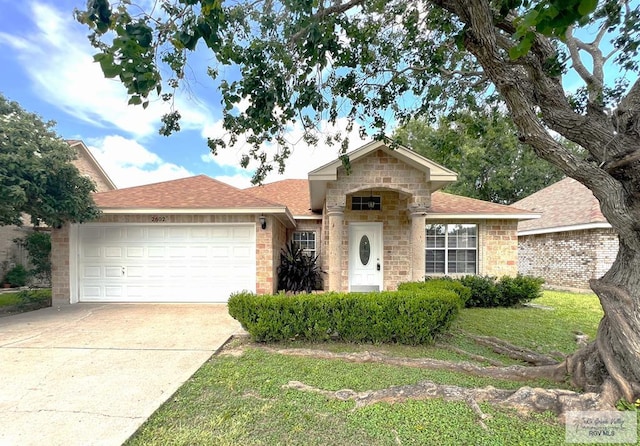 2602 E Mark Cir, Harlingen, TX 78550 - view of front of home with a garage, driveway, roof with shingles, brick siding, and a front lawn
