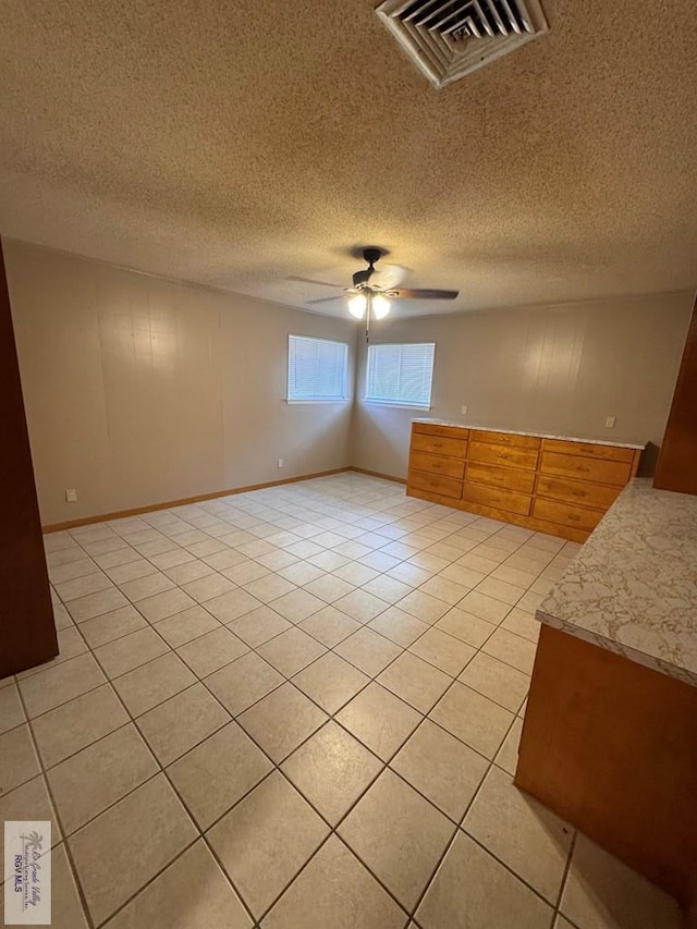 unfurnished room with light tile patterned floors, a textured ceiling, and ceiling fan