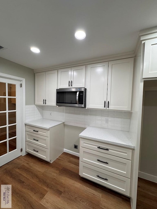 kitchen with backsplash, dark hardwood / wood-style floors, and white cabinetry