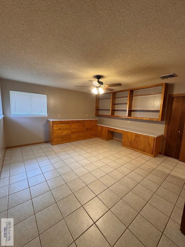 interior space featuring light tile patterned floors, a textured ceiling, and ceiling fan