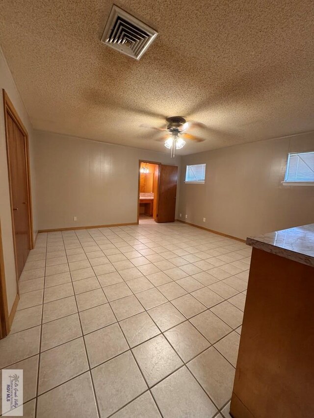 tiled empty room with a textured ceiling and ceiling fan