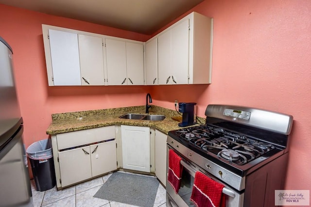 kitchen with stainless steel gas stove, sink, white cabinetry, and light tile patterned floors