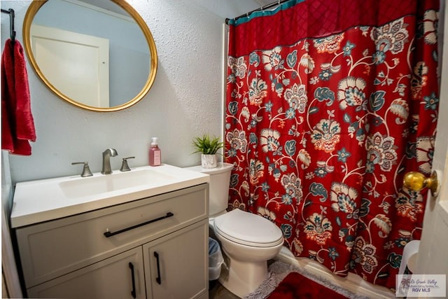 bathroom with curtained shower, toilet, and vanity