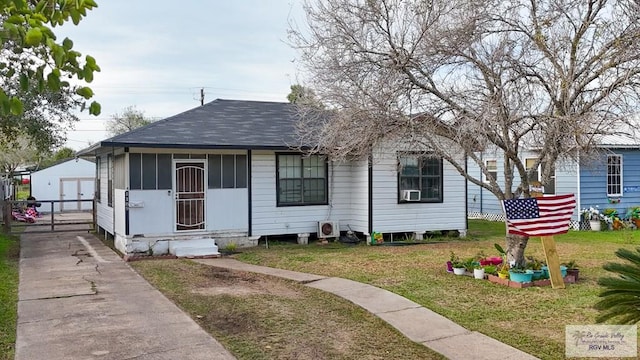 bungalow-style home with cooling unit and a front lawn