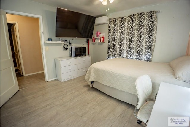 bedroom featuring ceiling fan, a wall mounted AC, and light hardwood / wood-style floors