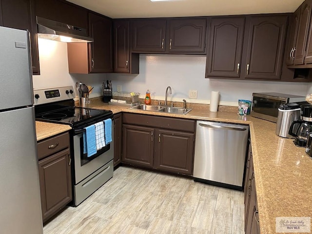 2010 El Dorado Ave, Rancho Viejo, TX 78575 - kitchen with appliances with stainless steel finishes, under cabinet range hood, a sink, light countertops, and light wood-style flooring