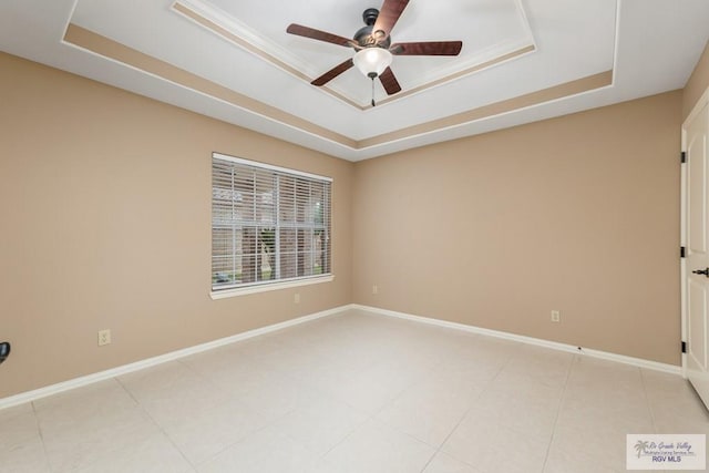 tiled empty room featuring ceiling fan and a tray ceiling