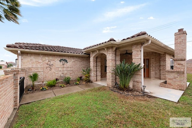 mediterranean / spanish home featuring a front lawn and ceiling fan