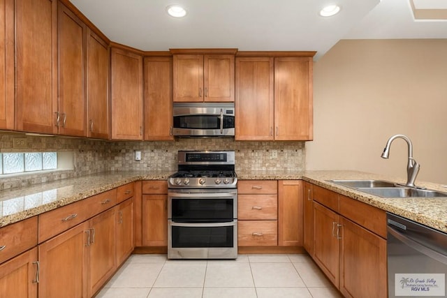 kitchen featuring light stone countertops, appliances with stainless steel finishes, sink, and light tile patterned floors