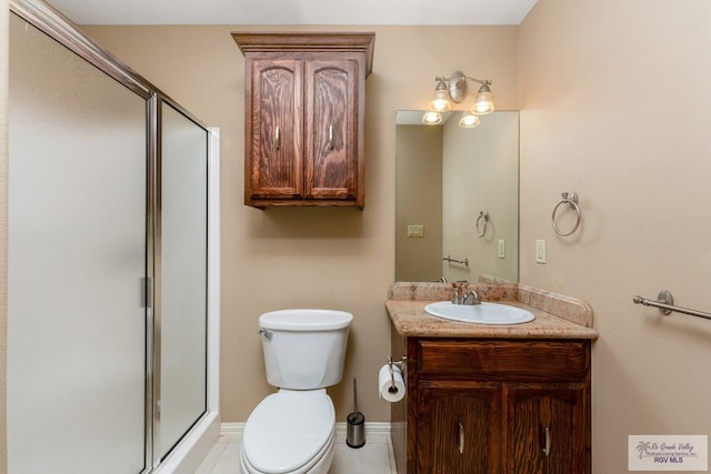 bathroom with vanity, toilet, and a shower with door