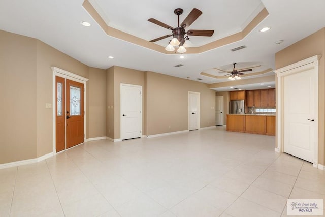 unfurnished living room featuring ornamental molding, a raised ceiling, and ceiling fan