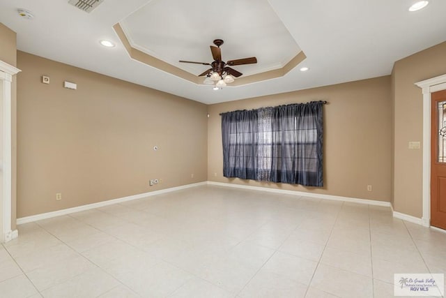 tiled spare room featuring ceiling fan and a tray ceiling