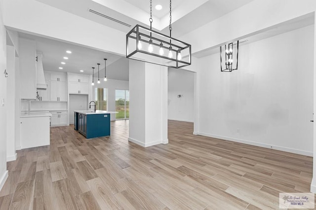 interior space with light hardwood / wood-style floors, a towering ceiling, and sink