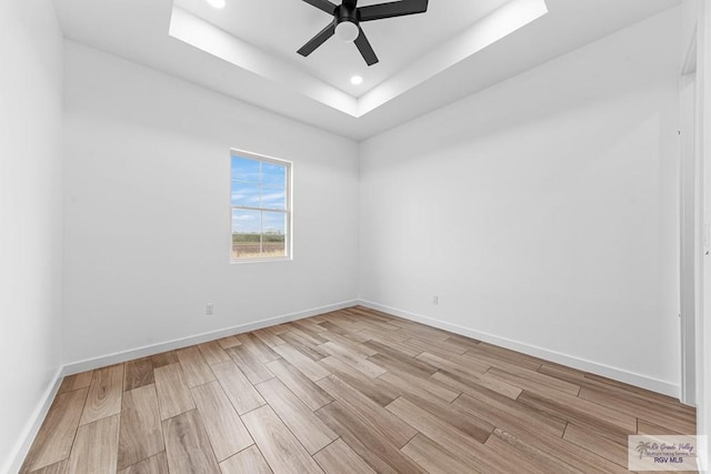 unfurnished room featuring a raised ceiling and ceiling fan