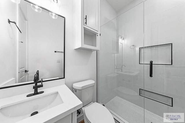 bathroom with a shower with door, vanity, and toilet