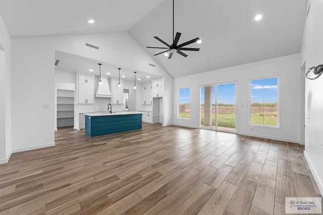 unfurnished living room with ceiling fan, sink, and high vaulted ceiling