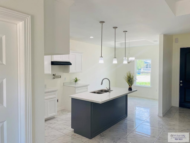 kitchen with pendant lighting, white cabinetry, sink, and a kitchen island with sink