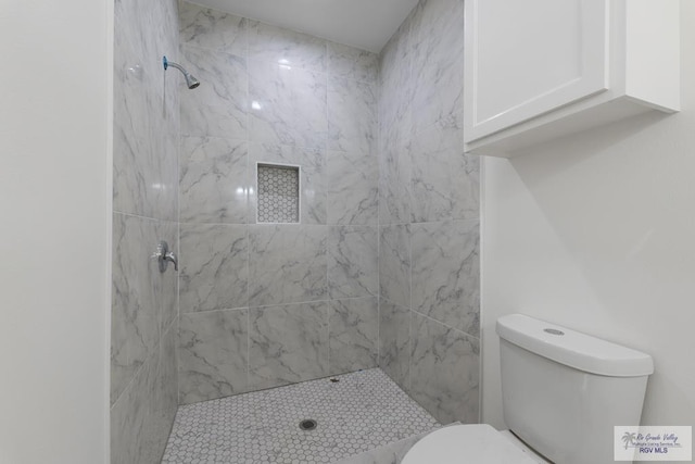 bathroom with tiled shower and toilet