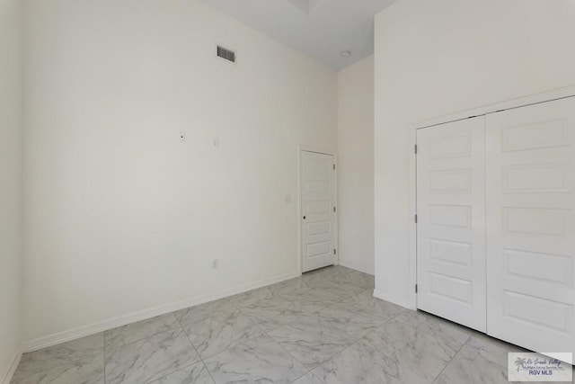 unfurnished bedroom featuring a high ceiling and a closet