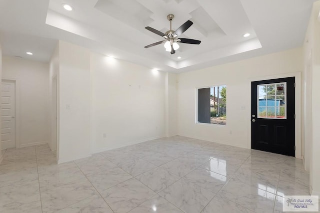 empty room with a raised ceiling and ceiling fan