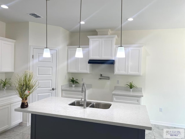 kitchen featuring white cabinets, decorative light fixtures, a kitchen island with sink, and sink