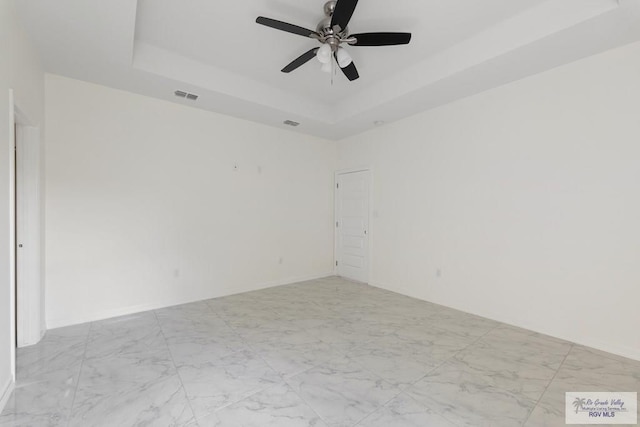 empty room featuring a tray ceiling and ceiling fan