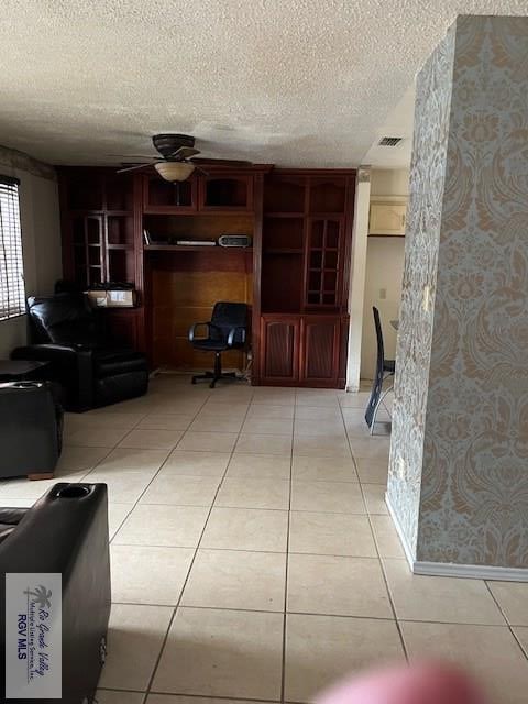 living room with ceiling fan, visible vents, a textured ceiling, and light tile patterned flooring