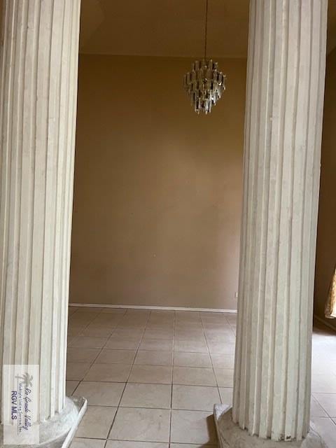 unfurnished dining area featuring light tile patterned floors, baseboards, and an inviting chandelier