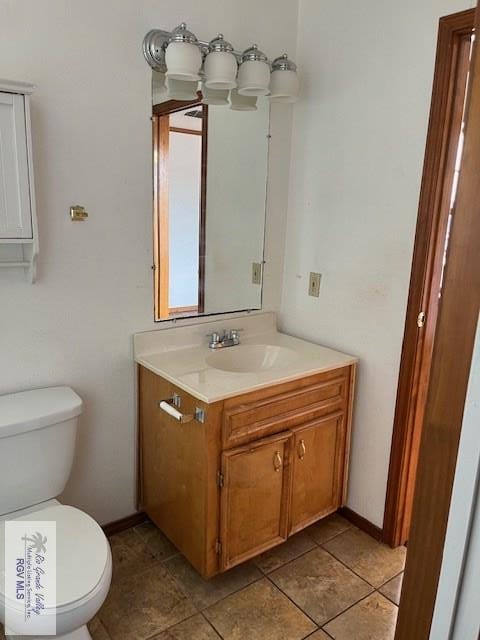 half bathroom with tile patterned floors, baseboards, toilet, and vanity