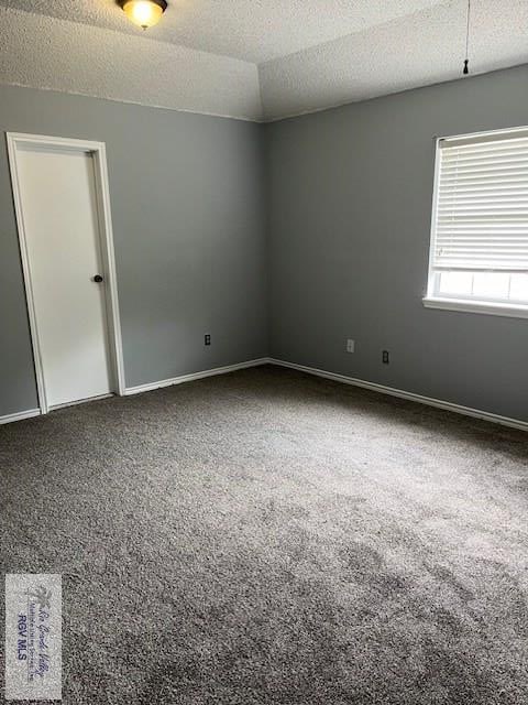 carpeted empty room with baseboards, a textured ceiling, and lofted ceiling