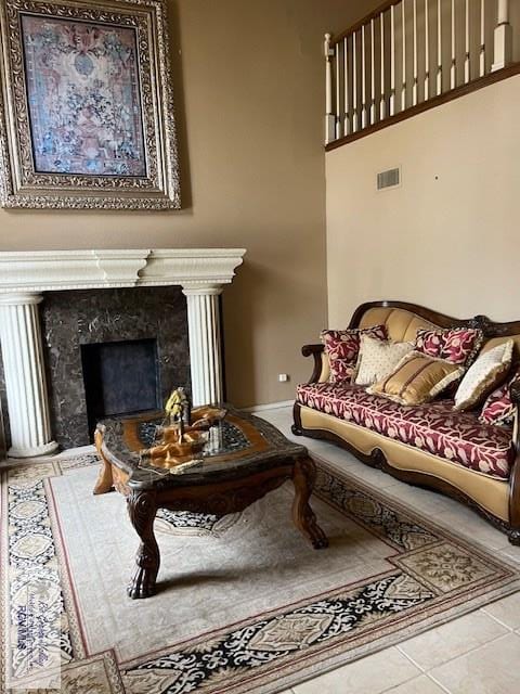 living room with tile patterned floors, baseboards, visible vents, and a high end fireplace