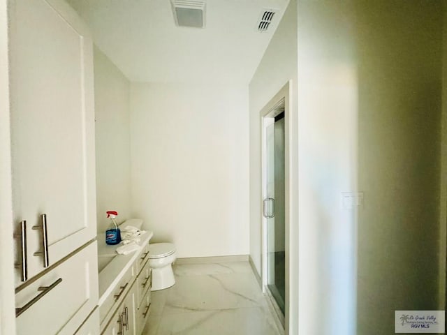 bathroom with vanity, toilet, and a shower with door