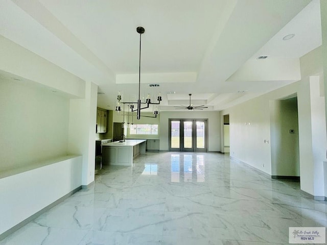 interior space with ceiling fan, sink, hanging light fixtures, a tray ceiling, and a kitchen island