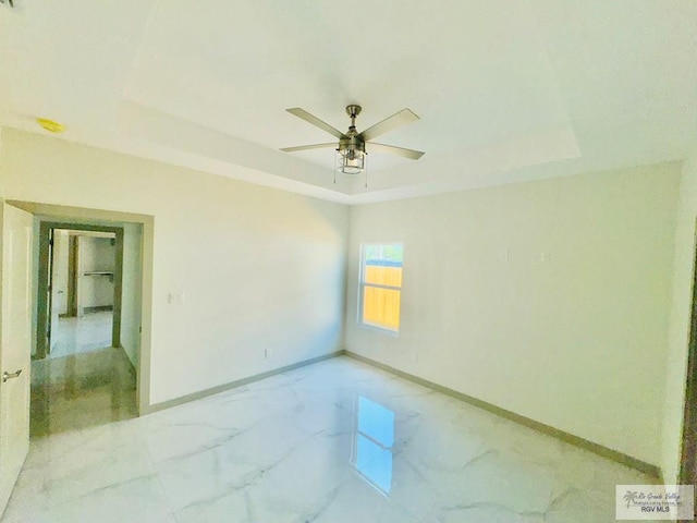 spare room with a tray ceiling and ceiling fan