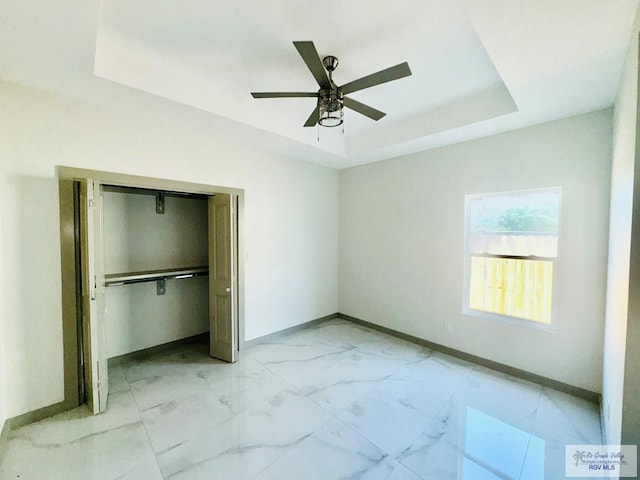 unfurnished bedroom featuring a raised ceiling, ceiling fan, and a closet