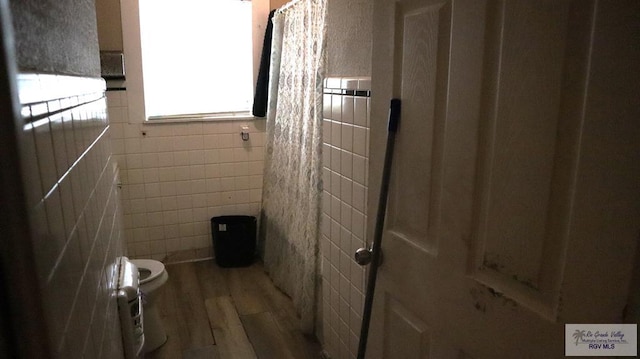 bathroom featuring hardwood / wood-style floors, toilet, and tile walls