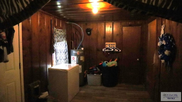 interior space featuring wooden walls, water heater, and dark wood-type flooring