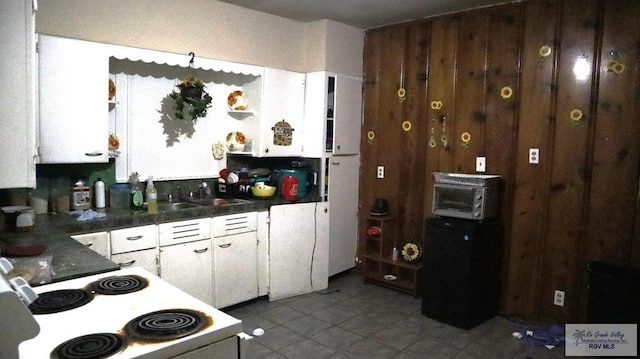 kitchen with white cabinets, light tile patterned floors, white electric stove, and sink