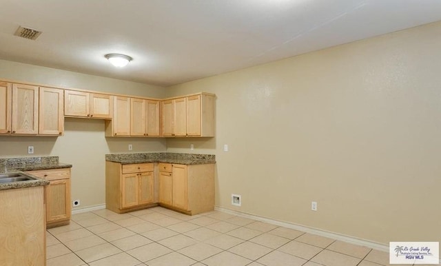 kitchen with light brown cabinetry, light tile patterned flooring, and sink