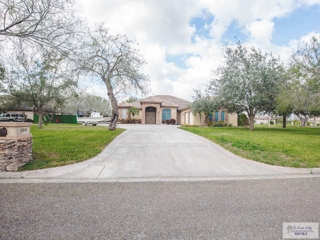 100 Paloma St, San Benito, TX 78586 - mediterranean / spanish-style home with a front lawn, an attached garage, driveway, and stucco siding
