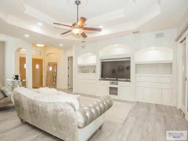 100 Paloma St, San Benito, TX 78586 - living room with built in shelves, arched walkways, ceiling fan, light wood-style floors, and a raised ceiling