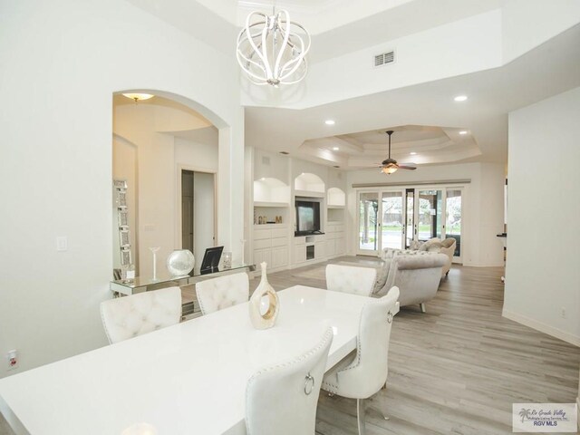 100 Paloma St, San Benito, TX 78586 - dining space with baseboards, recessed lighting, arched walkways, light wood-style floors, and a raised ceiling