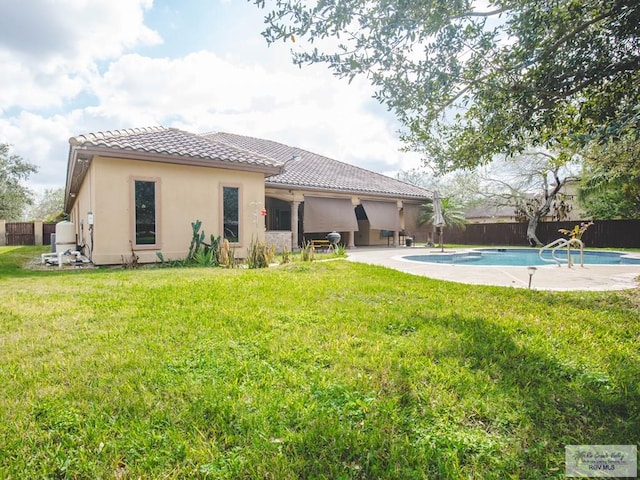100 Paloma St, San Benito, TX 78586 - rear view of house with stucco siding, a lawn, a fenced backyard, a fenced in pool, and a tiled roof