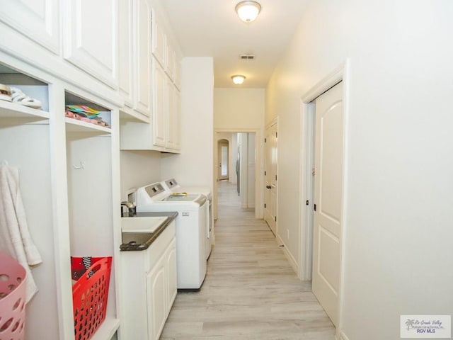 100 Paloma St, San Benito, TX 78586 - washroom featuring visible vents, cabinet space, a sink, light wood-style floors, and washer and clothes dryer