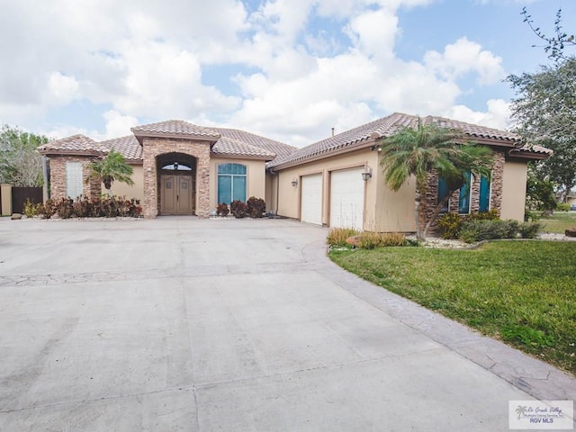 100 Paloma St, San Benito, TX 78586 - mediterranean / spanish home with a front lawn, a tiled roof, stucco siding, a garage, and driveway